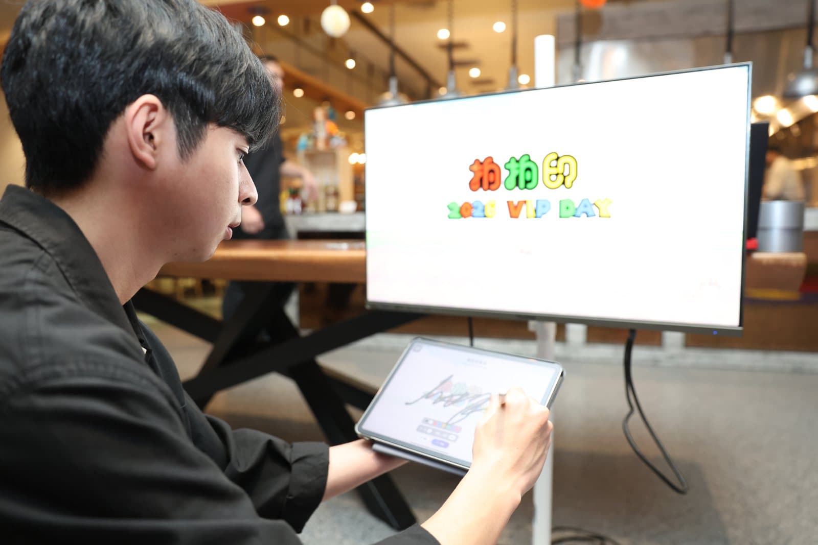 賓客在平板上手寫簽名，筆跡同步上大螢幕