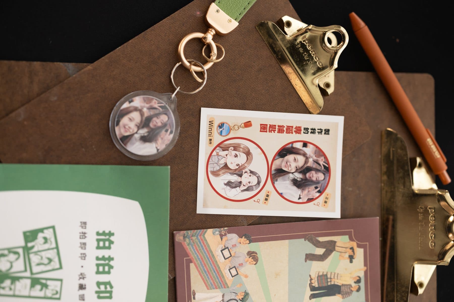 桌面上的壓克力鑰匙圈成品，旁邊有印同一張照片的貼紙與活動 DM