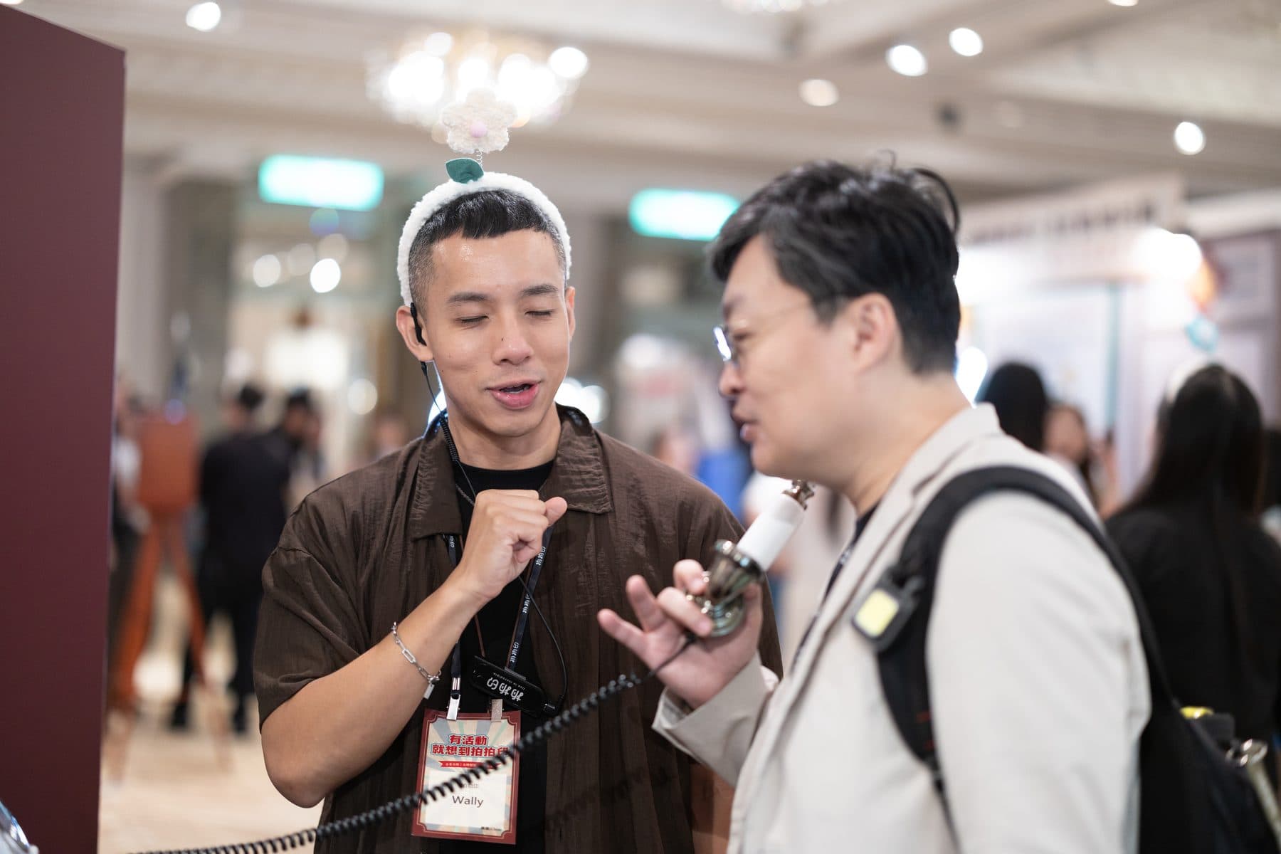 賓客手持話筒在影音留聲機前錄製留言，體驗顧問在旁引導