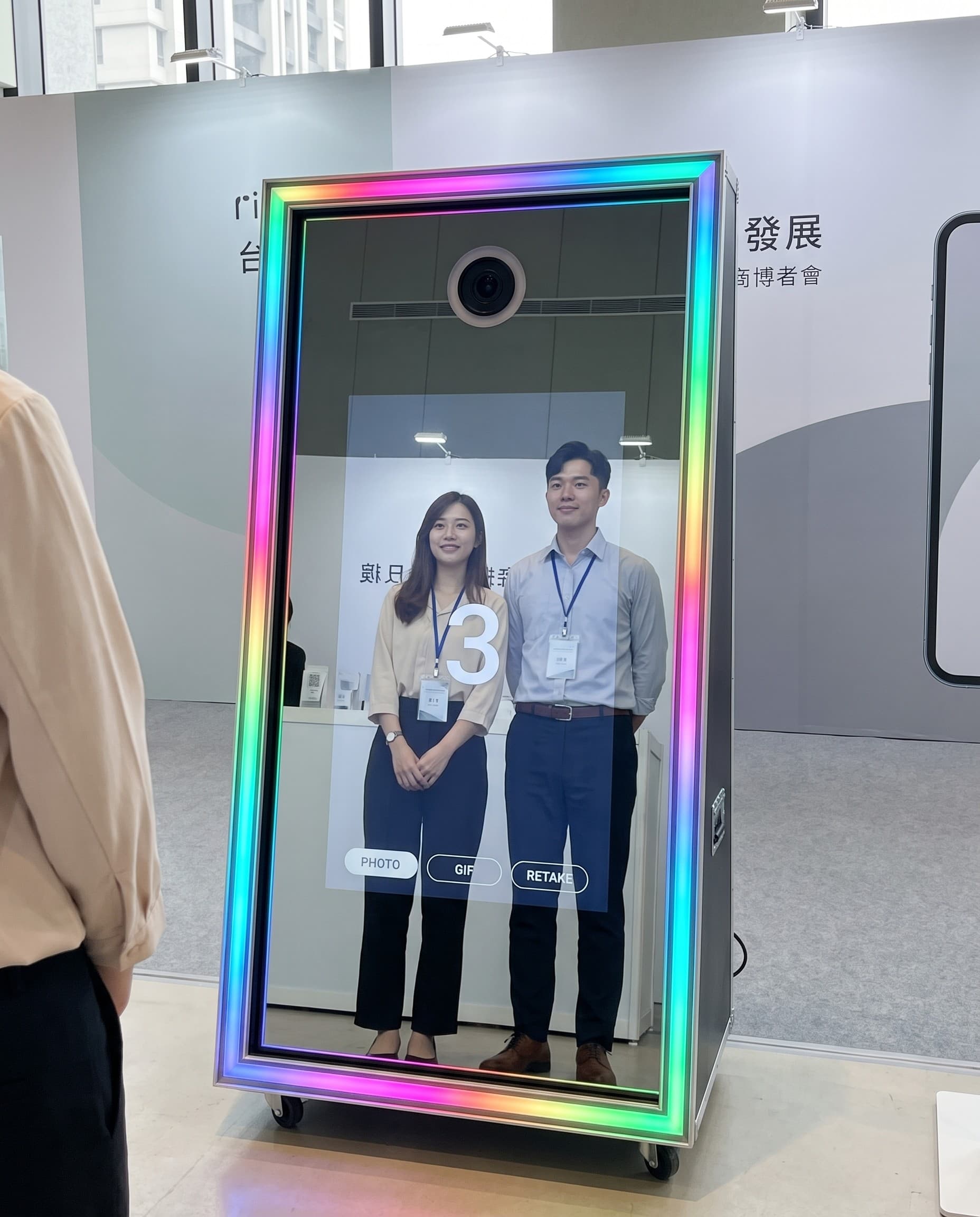 品牌發表會展場，賓客與品牌人員在魔鏡拍貼機前互動拍照