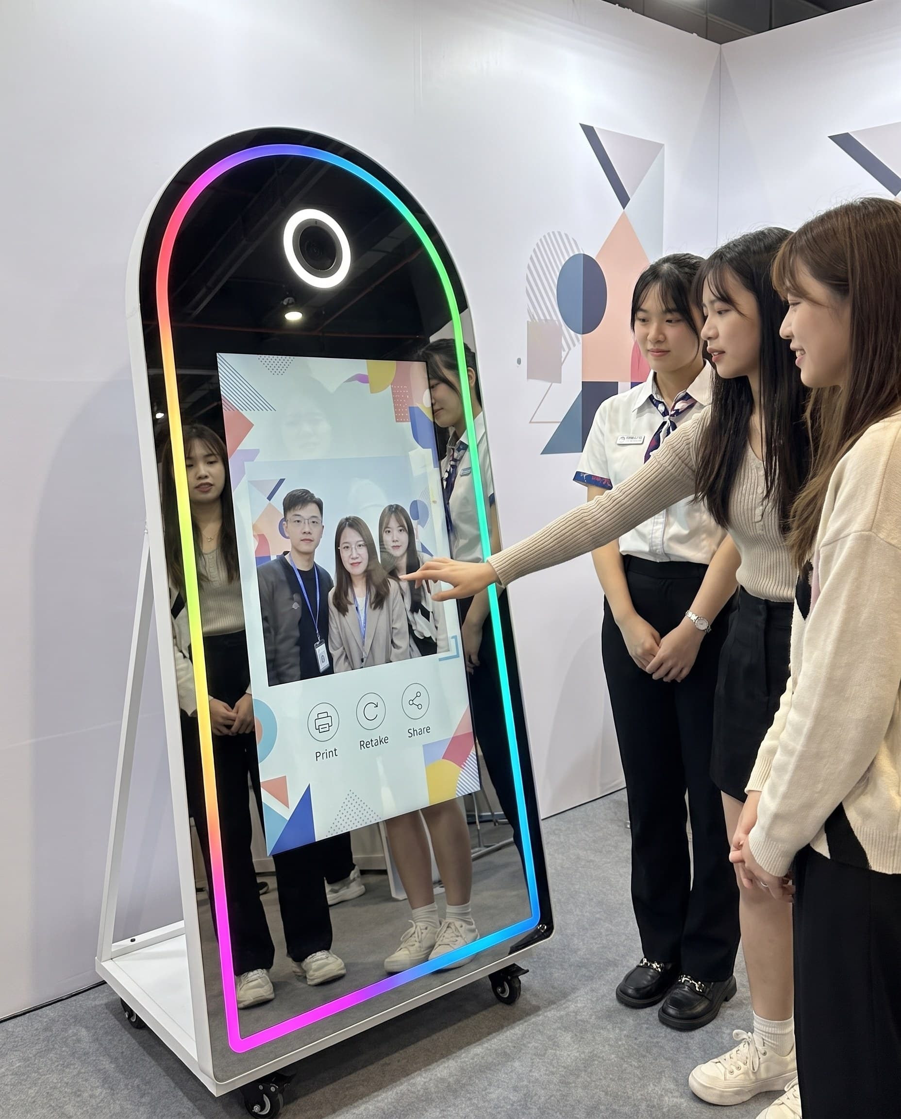 品牌發表會展場，賓客與品牌人員在魔鏡拍貼機前互動拍照