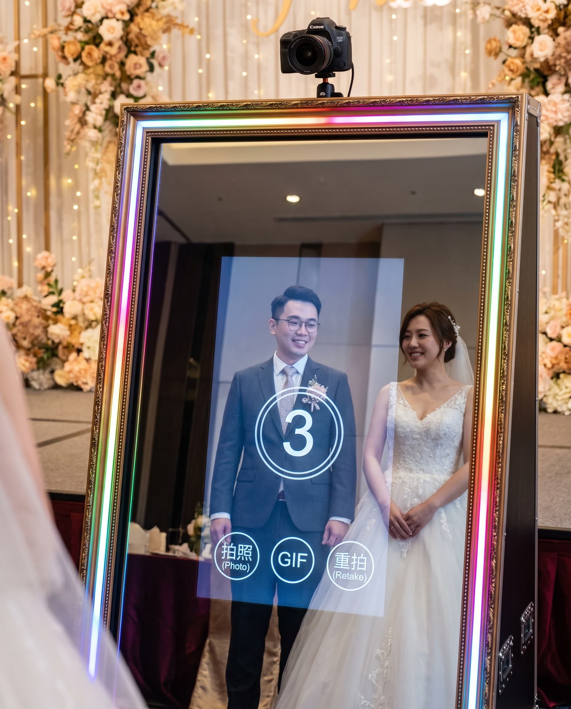 婚禮宴客現場，新人站在魔鏡拍貼機前甜蜜合照