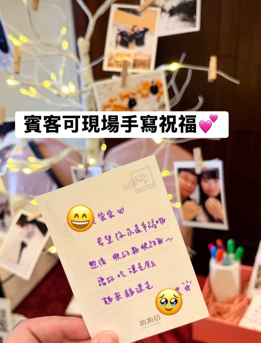 賓客在祝福留言樹旁,手持相片背面寫滿手寫祝福的明信片