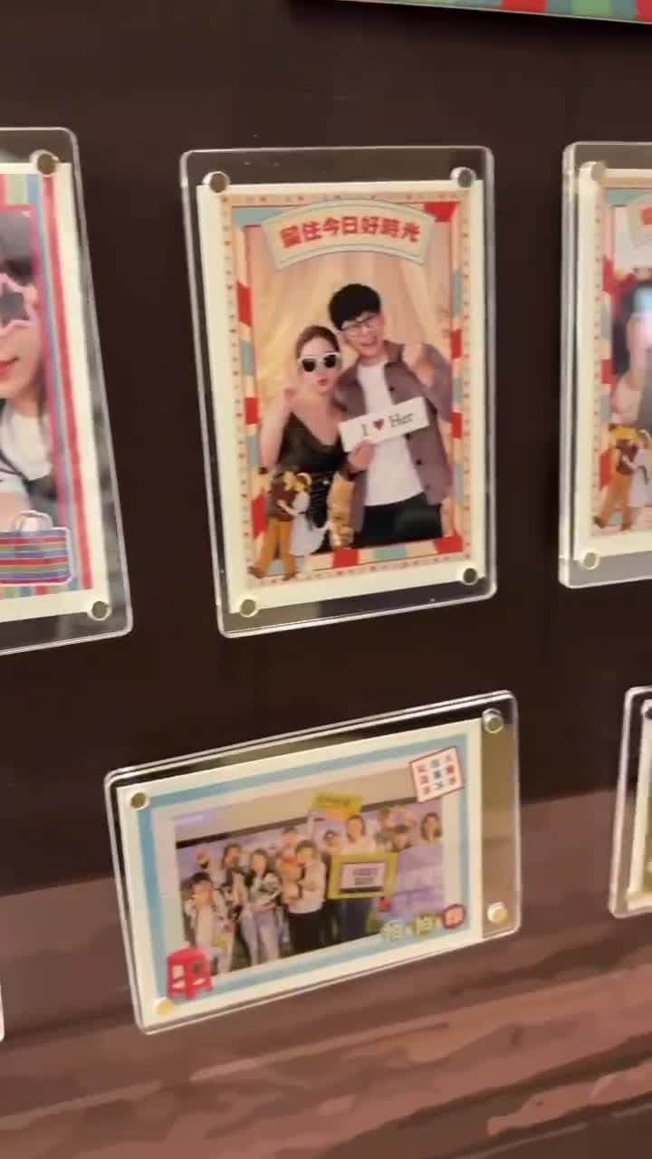 鏡頭掃過牆面上一排透明壓克力磁吸框,每一個都夾著一張客製邊框的拍貼相片