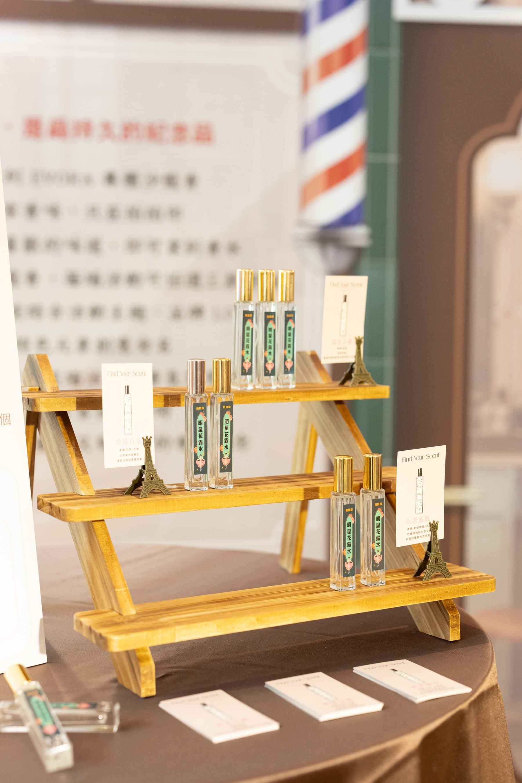 木質階梯展示架上排列多支客製香氛瓶,旁邊立有說明卡,牆面文案寫著「獨藏持久的紀念品」