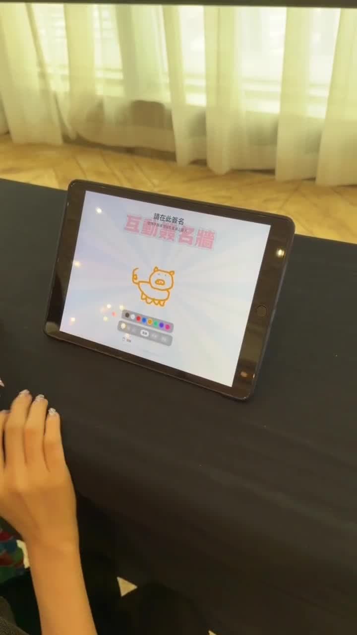 賓客在平板上簽名,鏡頭接著帶到布幕,簽名已經浮現在牆上
