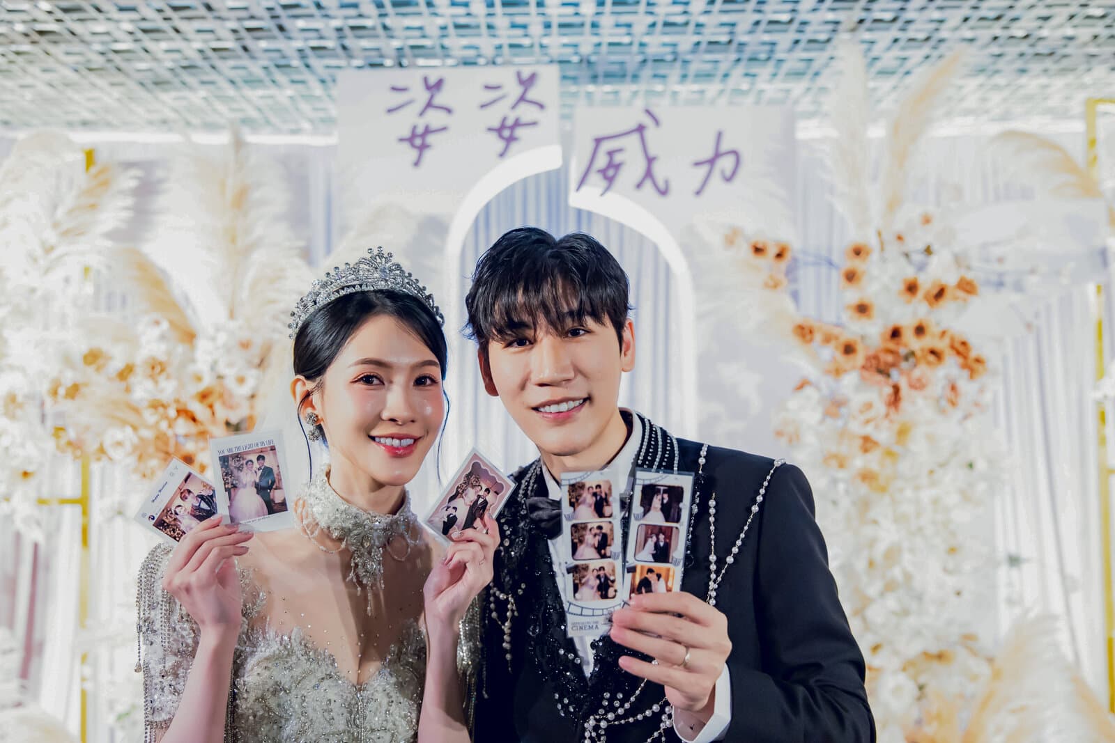 新人手持婚禮拍貼成品在婚禮背板前合照